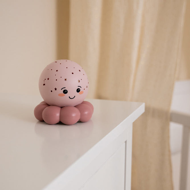 Pink octopus-shaped decorative item on a white surface with a blurred background