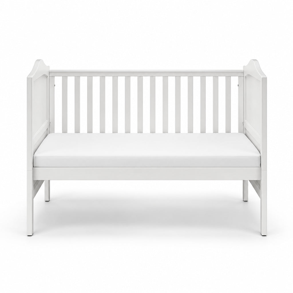 A white wooden baby crib with vertical slats and a matching white mattress, shown from a front-facing perspective on a seamless white background.