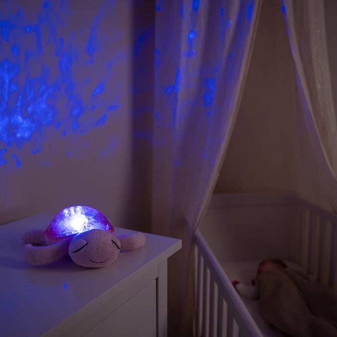 Plush turtle toy with glowing light on a nightstand in a dimly lit room.