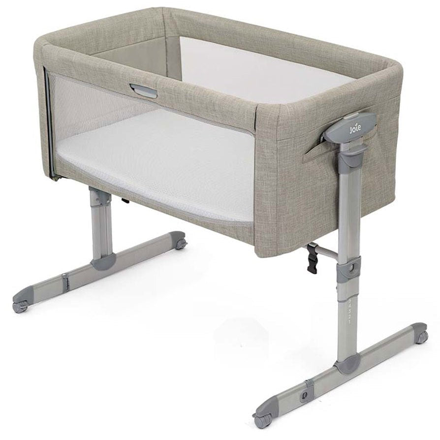 A Jola baby bassinet with a light beige textured fabric frame, white mesh sides, and a white mattress, supported by a gray adjustable metal stand on a white background.