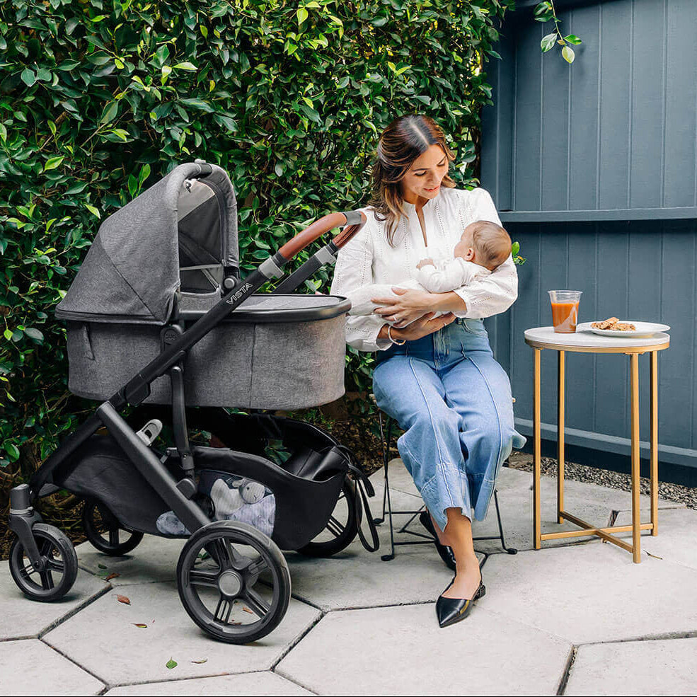 Woman holding a baby next to a stroller outdoors