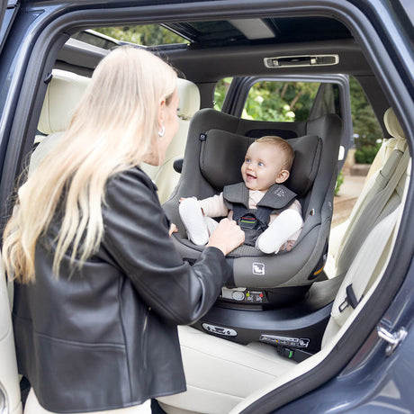 Woman adjusting a baby in a car seat inside a vehicle