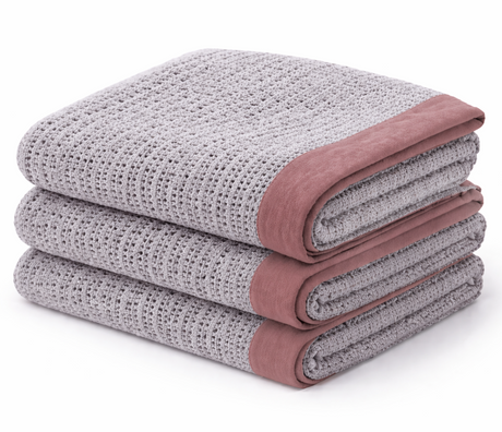 Stack of folded textured blankets with pink edges on a white background
