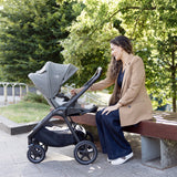 Woman sitting on a bench with a stroller in an urban park setting