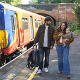Man and woman with a child walking on a train platform next to a colorful train.