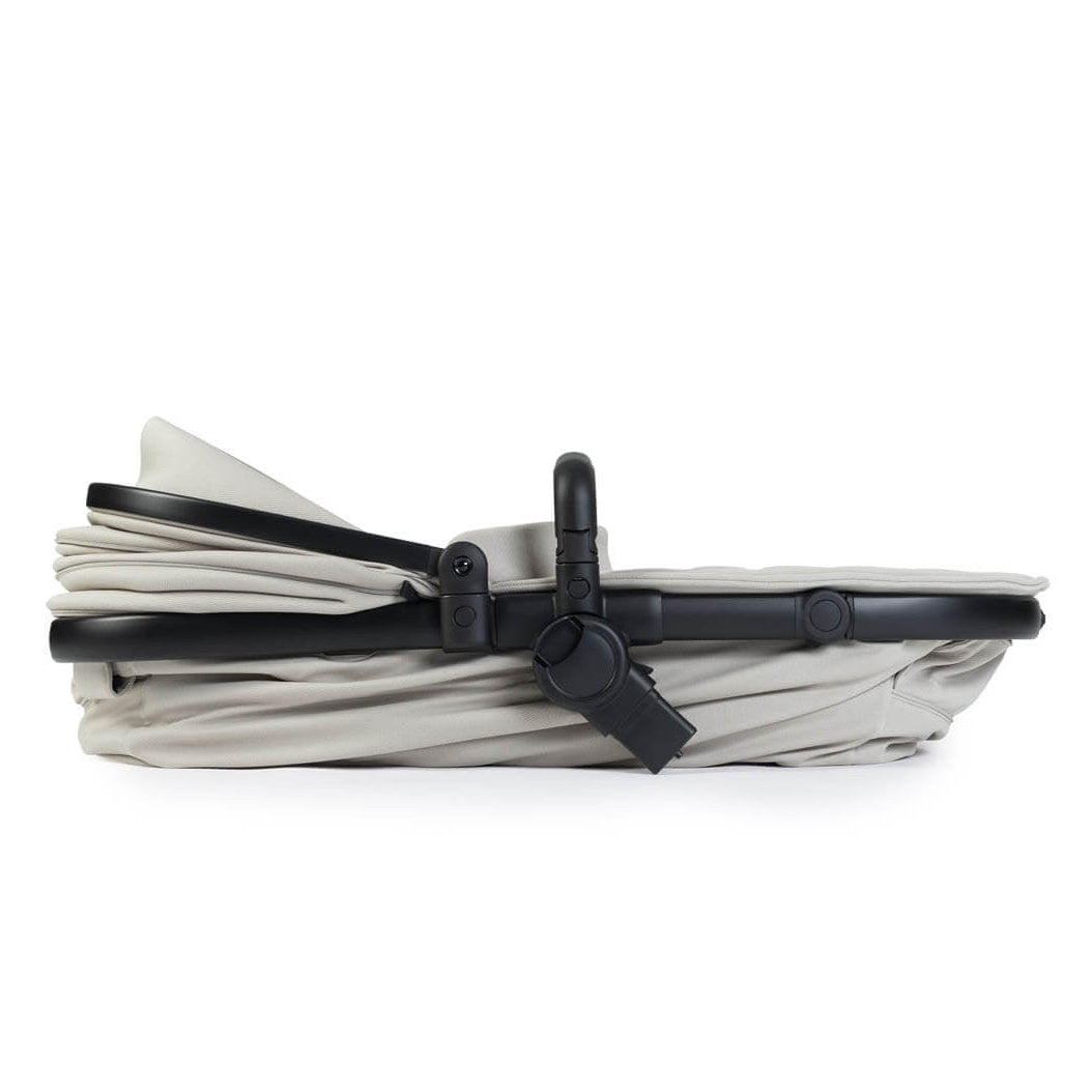 Folded baby bassinet with black straps on a white background