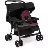 A compact double stroller in black with burgundy and green seat liners, shown from a three-quarter angle on a white background.