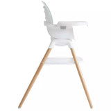 A modern white baby high chair with light natural wood legs, shown from a side profile view against a solid white background.