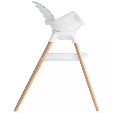 A modern high chair with a white molded plastic seat and tray, supported by four natural light wood legs, shown from a side profile on a solid white background.
