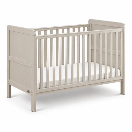 A light beige wooden convertible crib with vertical slats and a white mattress, shown on a clean white background.