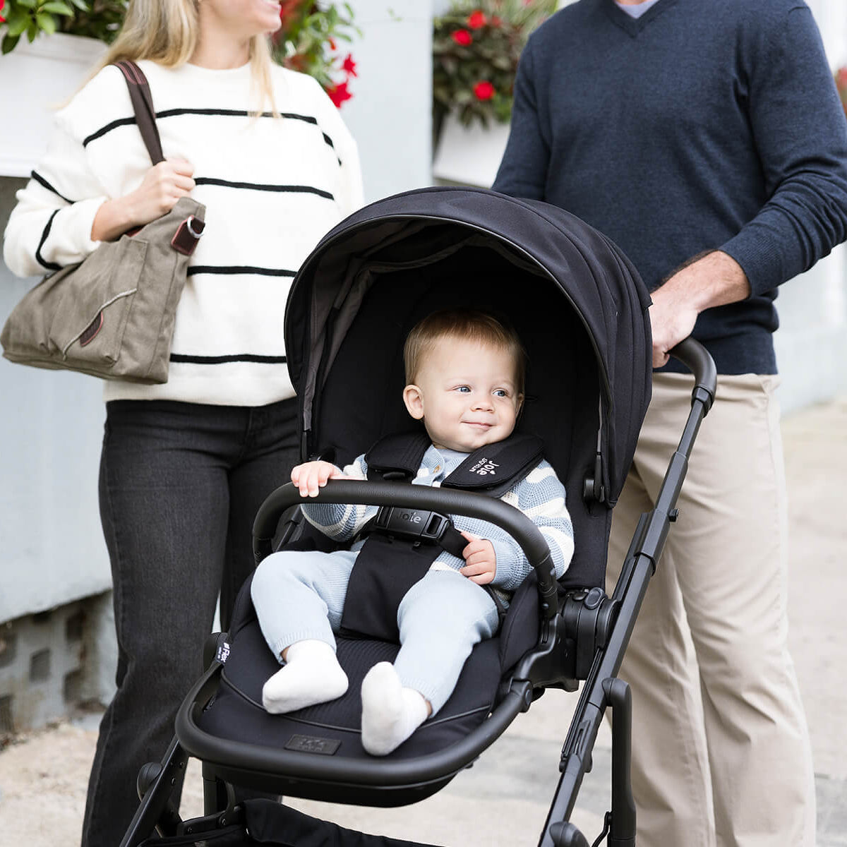 Baby in a stroller with parents standing outdoors