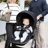 Baby in a stroller with parents standing outdoors