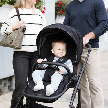Baby in a stroller with parents standing outdoors