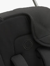 Close-up detail of a black stroller canopy showing the padded side panel, mesh ventilation fabric, and a circular embroidered logo.