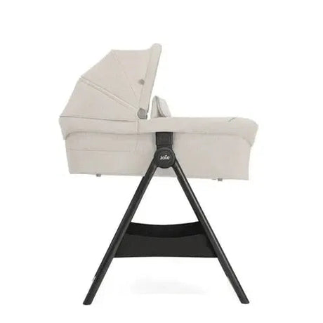 Baby bassinet with beige cover on a white background