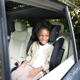 Child sitting in a car seat inside a vehicle with greenery outside
