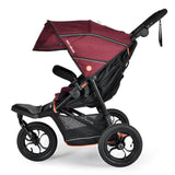 A stroller with a burgundy and black canopy, black frame, and three wheels, shown from a side profile on a white background.
