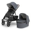 Gray stroller with attached bassinet on a white background