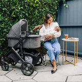 Woman holding a baby next to a stroller outdoors